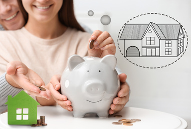 Image of Couple putting money into piggy bank for future house purchase, closeup