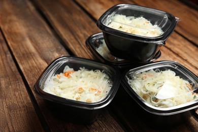 Photo of Plastic containers with tasty vegetable salad on wooden table. Food delivery service