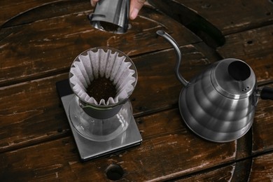 Photo of Cup with coffee, wave dripper and kettle on wooden table in cafe