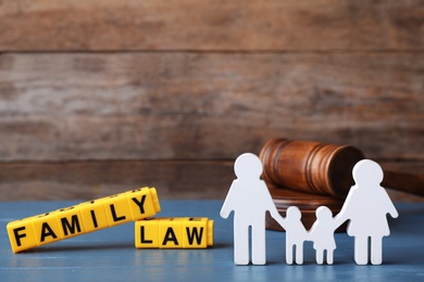 Photo of Figure in shape of people, cubes with words Family Law and gavel on blue wooden table