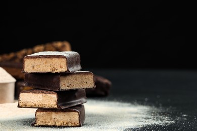 Photo of Tasty energy bars and protein powder on black table, closeup. Space for text