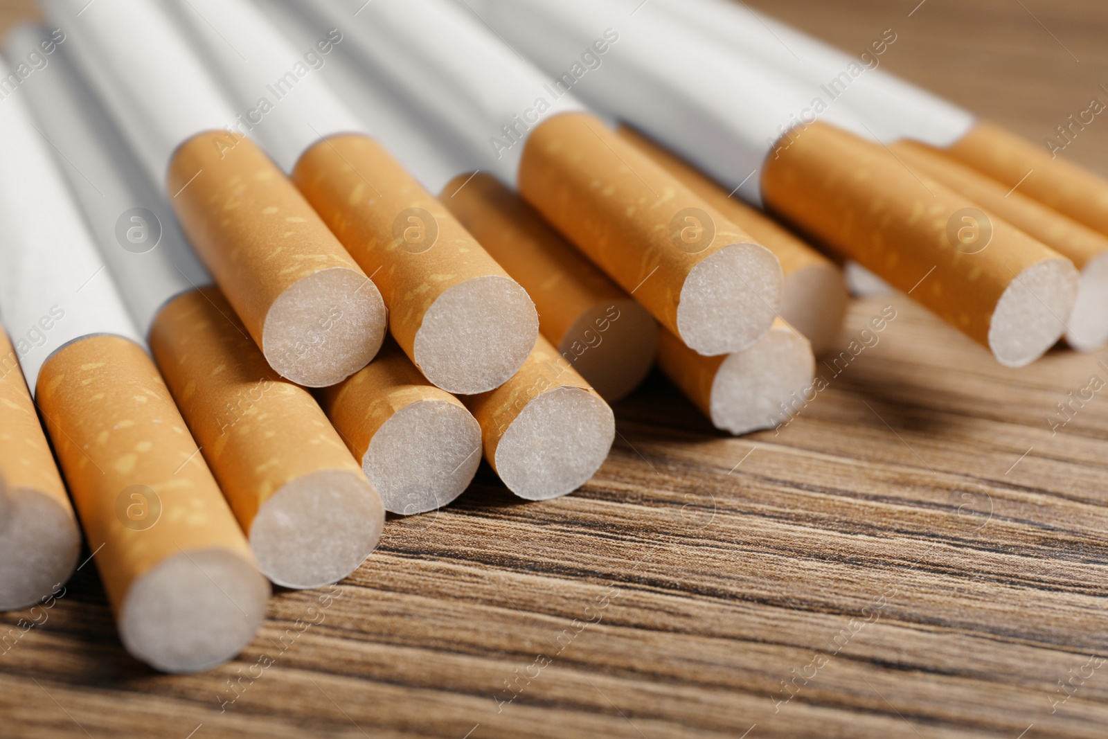 Photo of Pile of cigarettes on wooden table, closeup