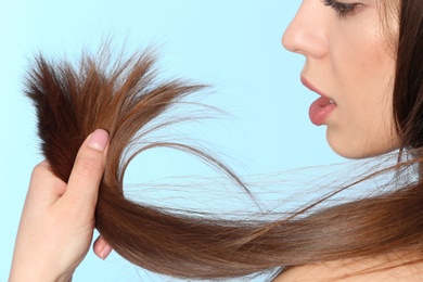 Photo of Woman with damaged hair on color background, closeup. Split ends