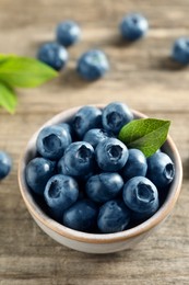 Bowl of tasty fresh blueberries on wooden table, closeup