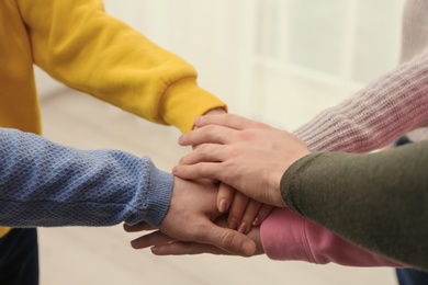Group of people holding their hands together on blurred background, closeup