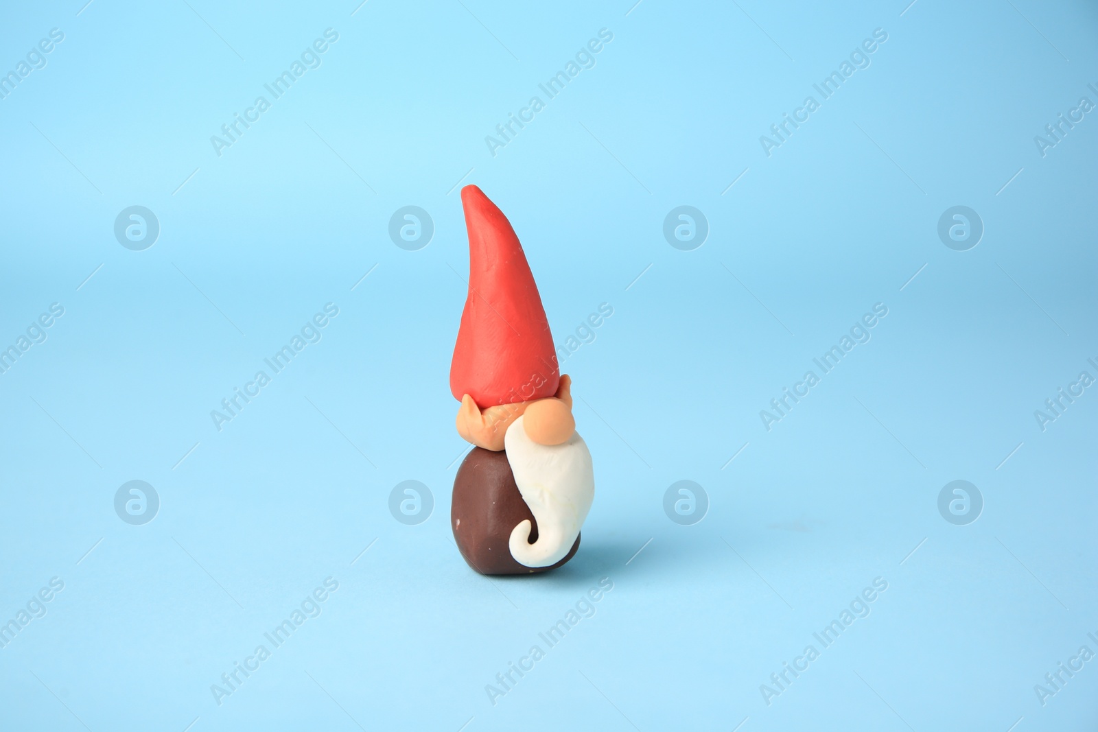 Photo of Dwarf made from plasticine on light blue background. Children's handmade ideas