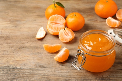 Photo of Composition with tasty tangerine jam on wooden table. Space for text