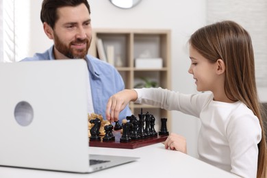 Photo of Father and daughter playing chess at home