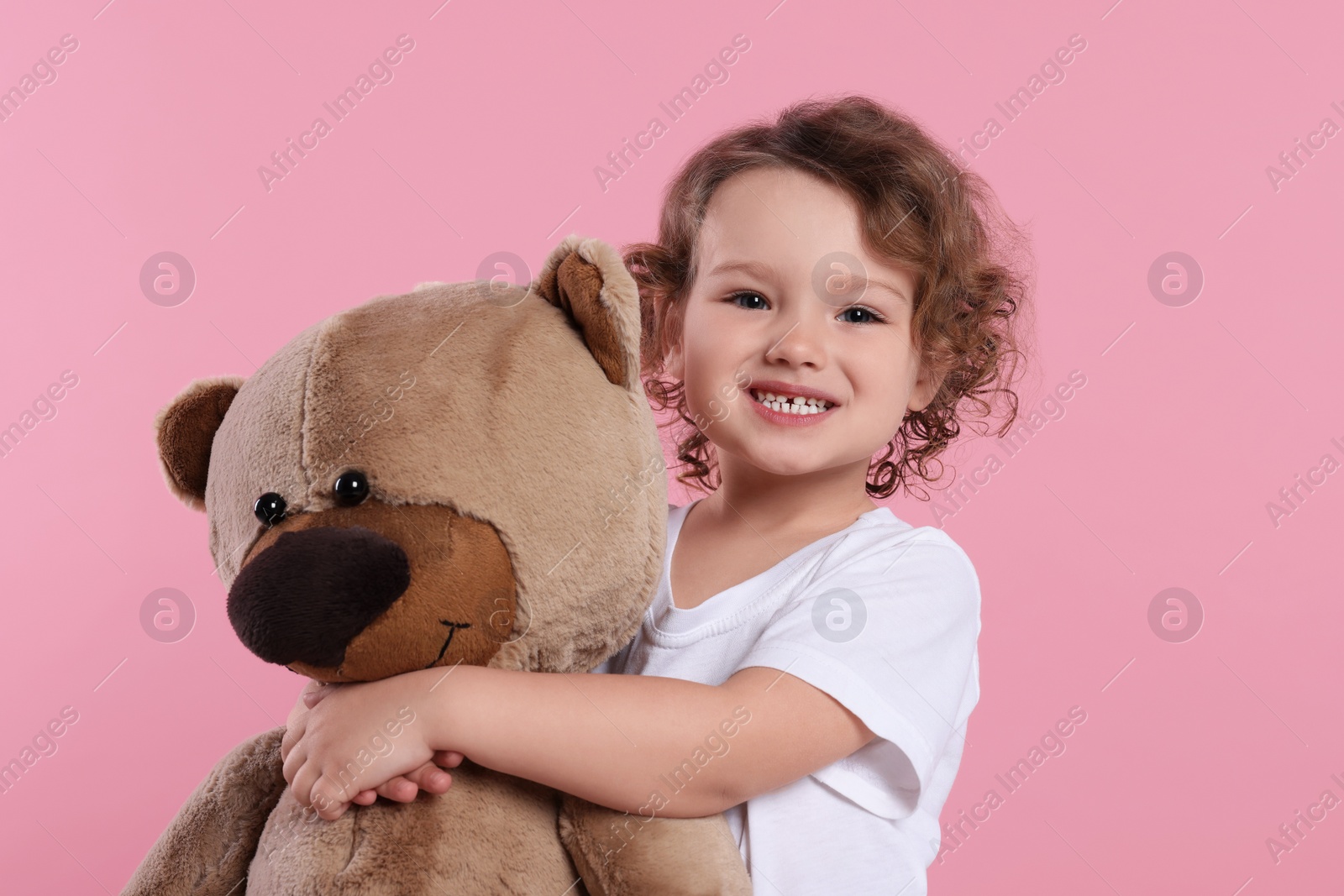 Photo of Cute little girl with teddy bear on pink background