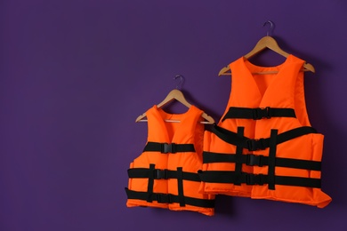 Photo of Orange life jackets on violet background. Space for text