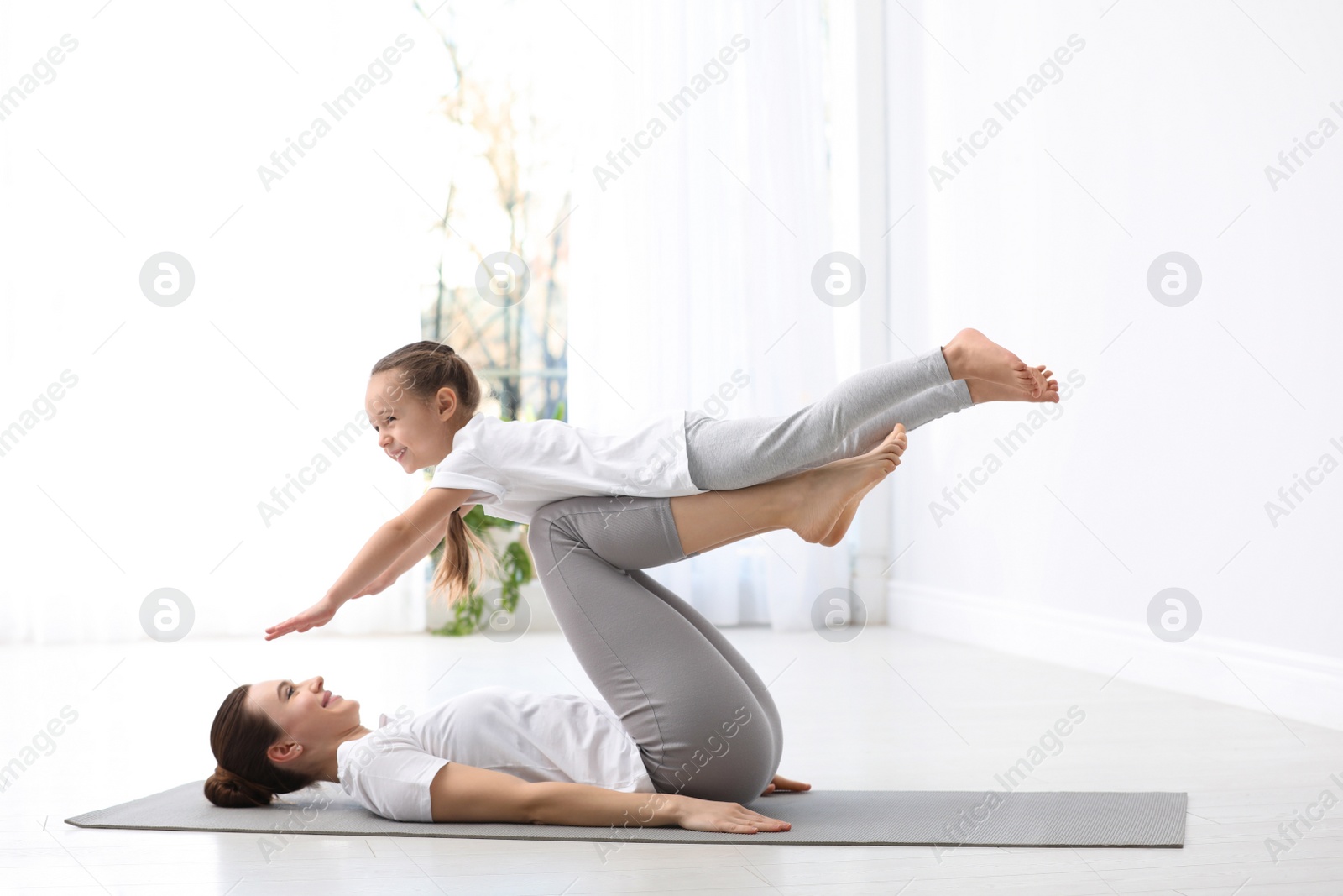 Photo of Young mother with little daughter practicing yoga at home