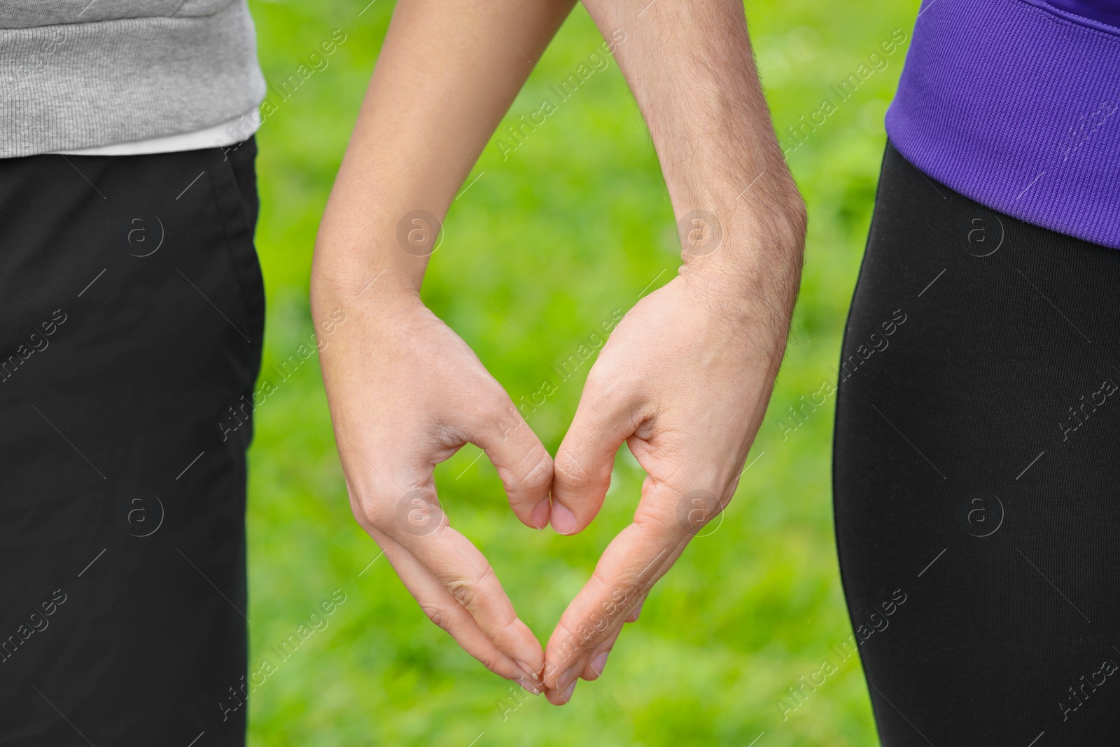 Photo of Couple making heart with hands outdoors, closeup