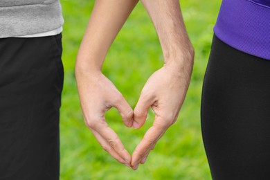 Photo of Couple making heart with hands outdoors, closeup