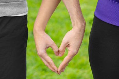 Couple making heart with hands outdoors, closeup