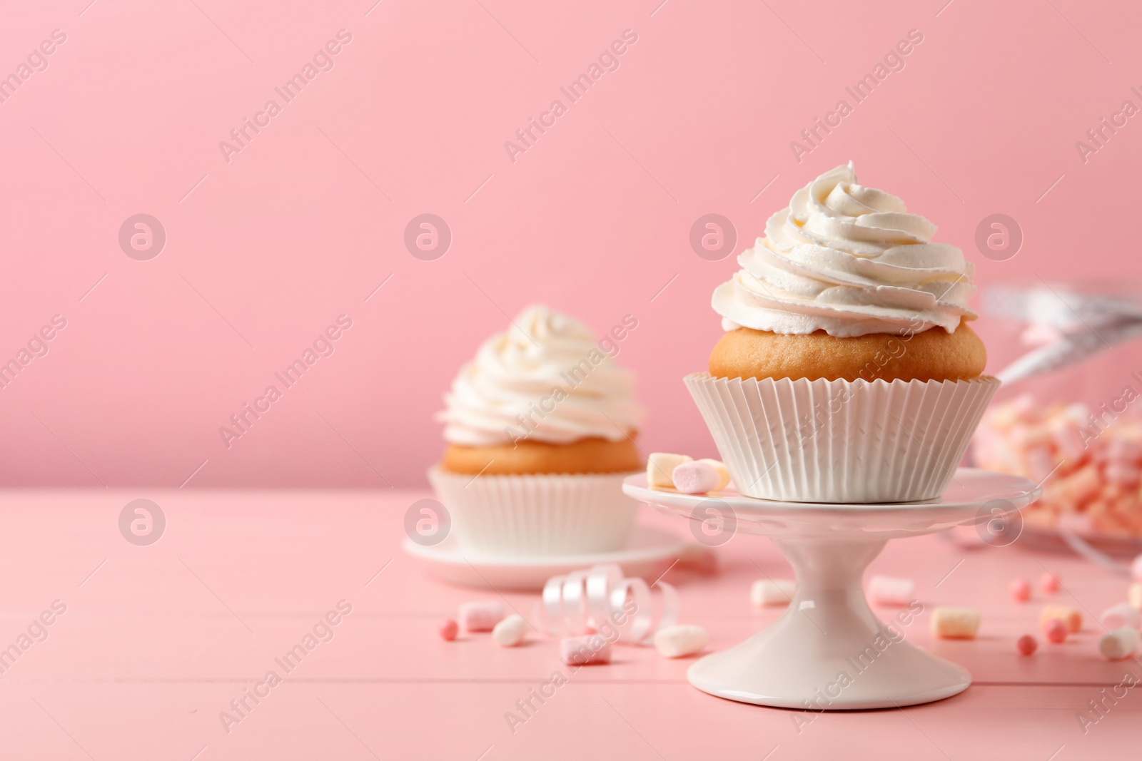 Photo of Delicious cupcakes decorated with cream on pink wooden table, space for text