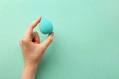 Photo of Woman with makeup sponge on mint color background, top view. Space for text