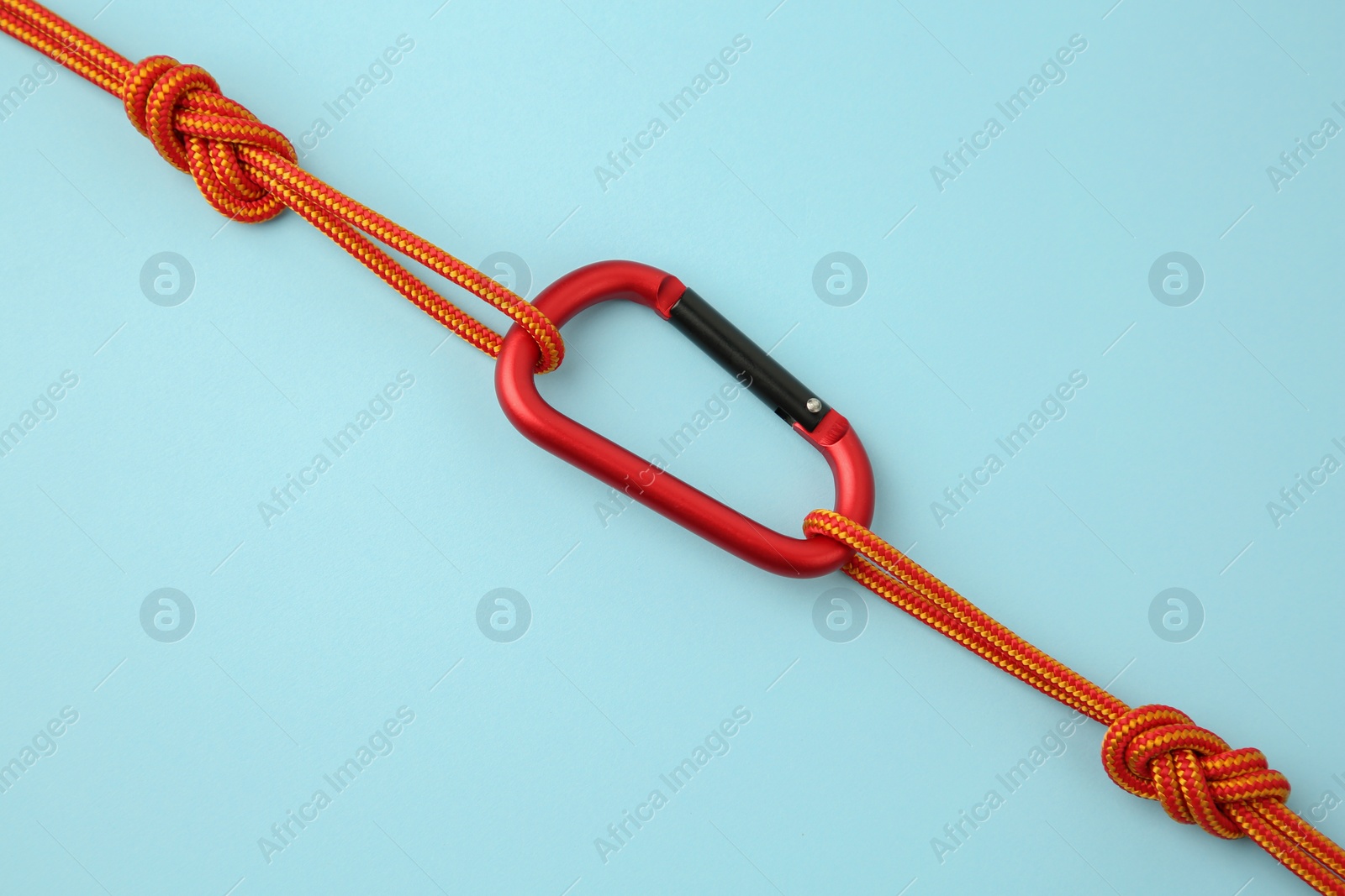 Photo of One metal carabiner with ropes on light blue background, top view