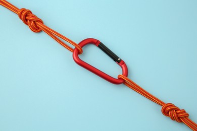 Photo of One metal carabiner with ropes on light blue background, top view
