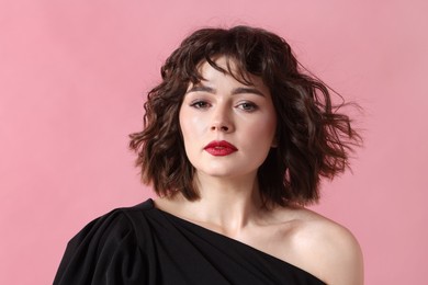 Portrait of beautiful young woman with wavy hairstyle on pink background