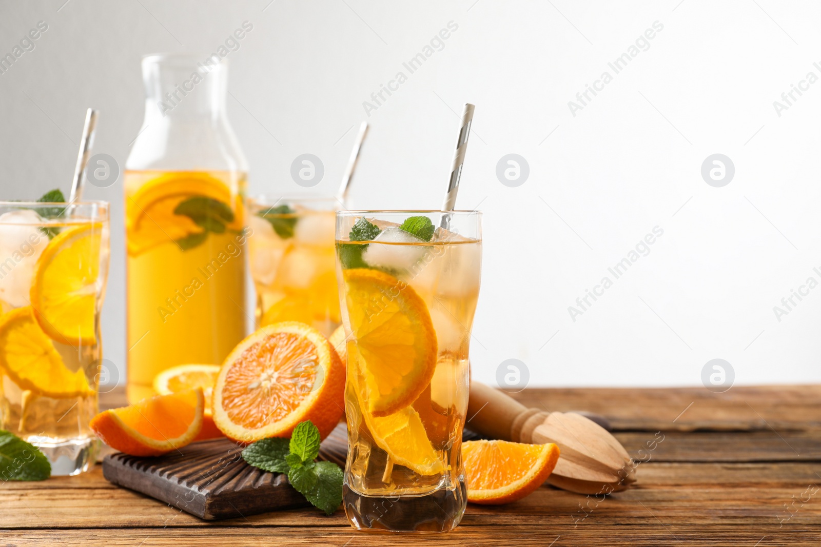 Photo of Delicious refreshing drink with orange slices on wooden table. Space for text