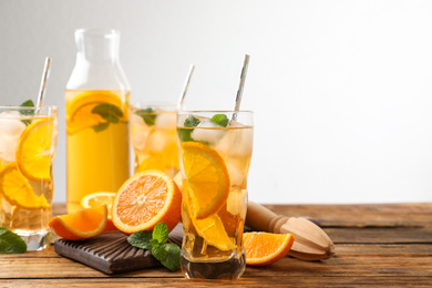 Photo of Delicious refreshing drink with orange slices on wooden table. Space for text