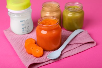 Photo of Healthy baby food, spoon and bottle of milk on pink background