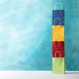 Photo of Colorful paper shopping bags on table against color background. Space for text