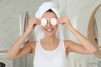 Happy young woman with cotton pads in bathroom