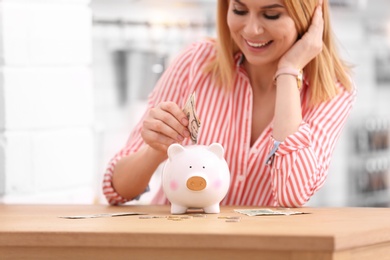 Photo of Woman with piggy bank and money at home