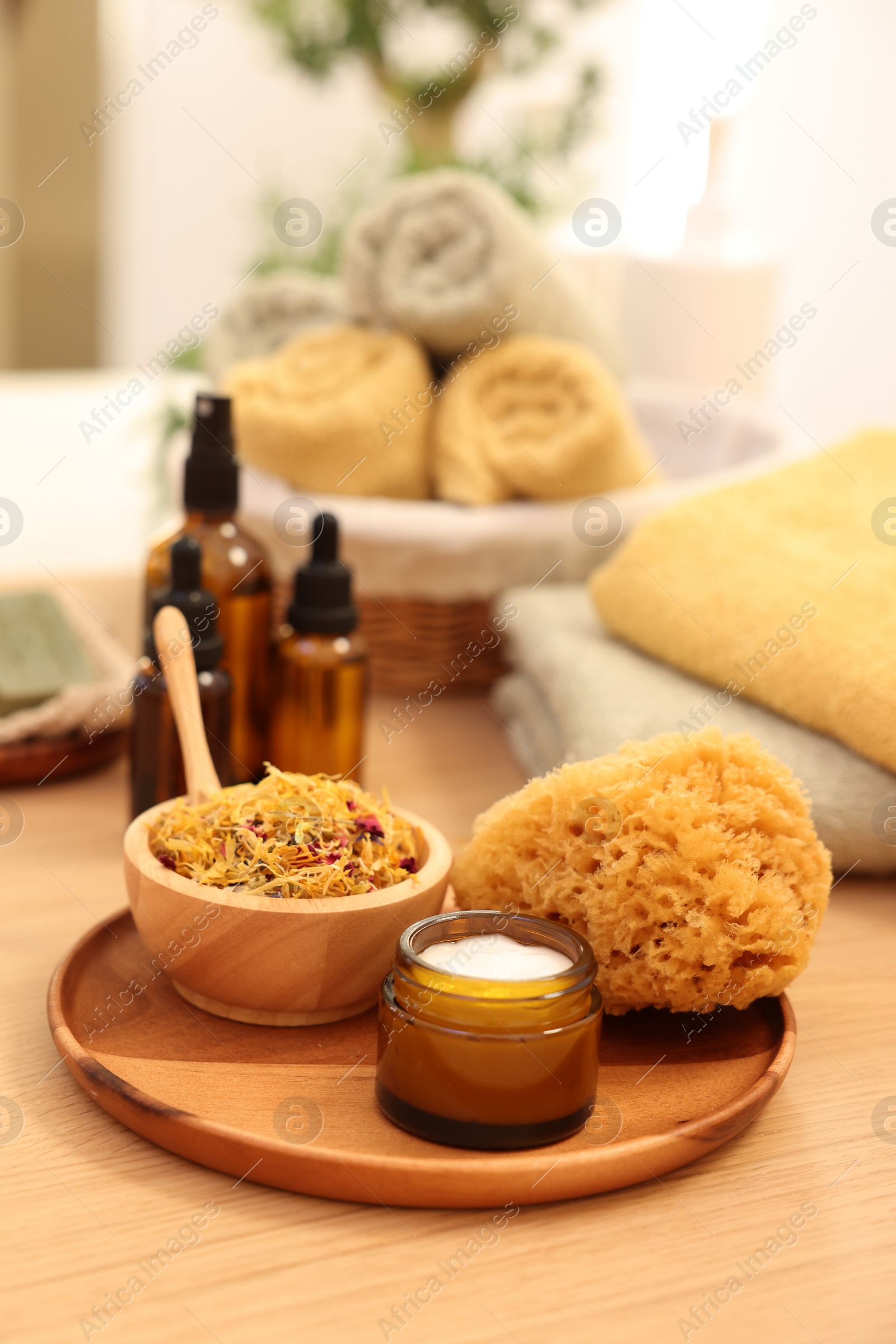 Photo of Dry flowers, loofah and jar with cream on wooden table indoors. Spa time