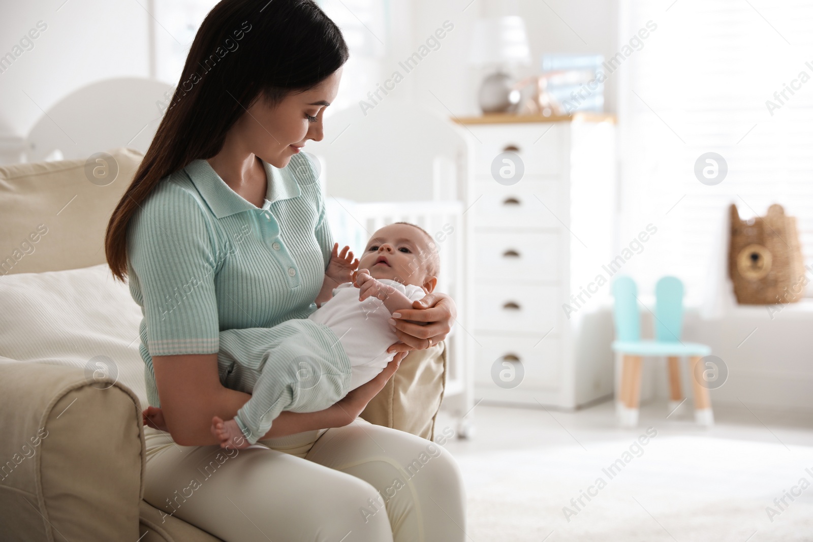 Photo of Young woman with her cute baby at home, space for text