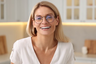 Portrait of smiling woman with stylish glasses in kitchen