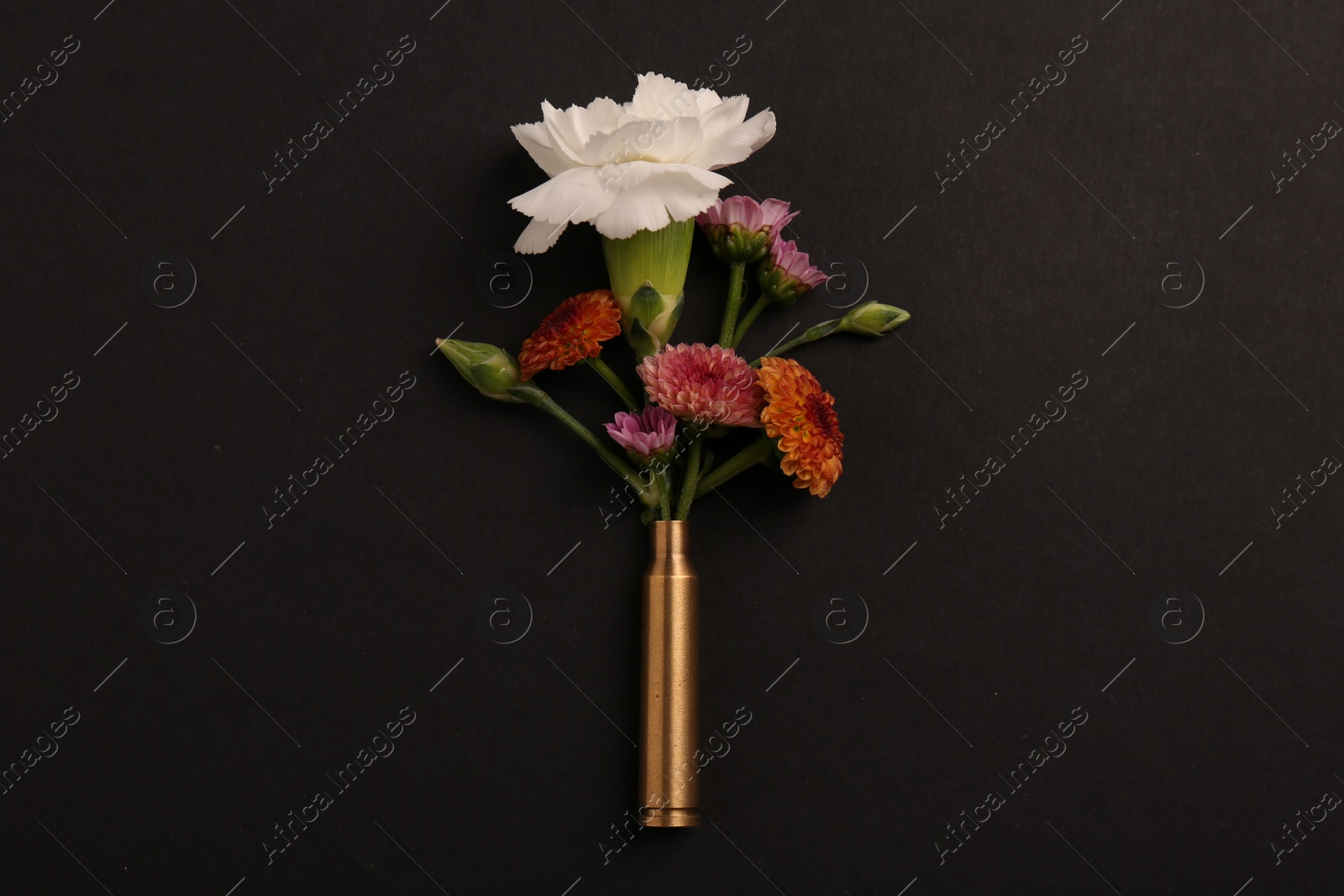 Photo of Bullet case with beautiful flowers on black background, top view