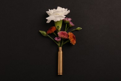 Bullet case with beautiful flowers on black background, top view