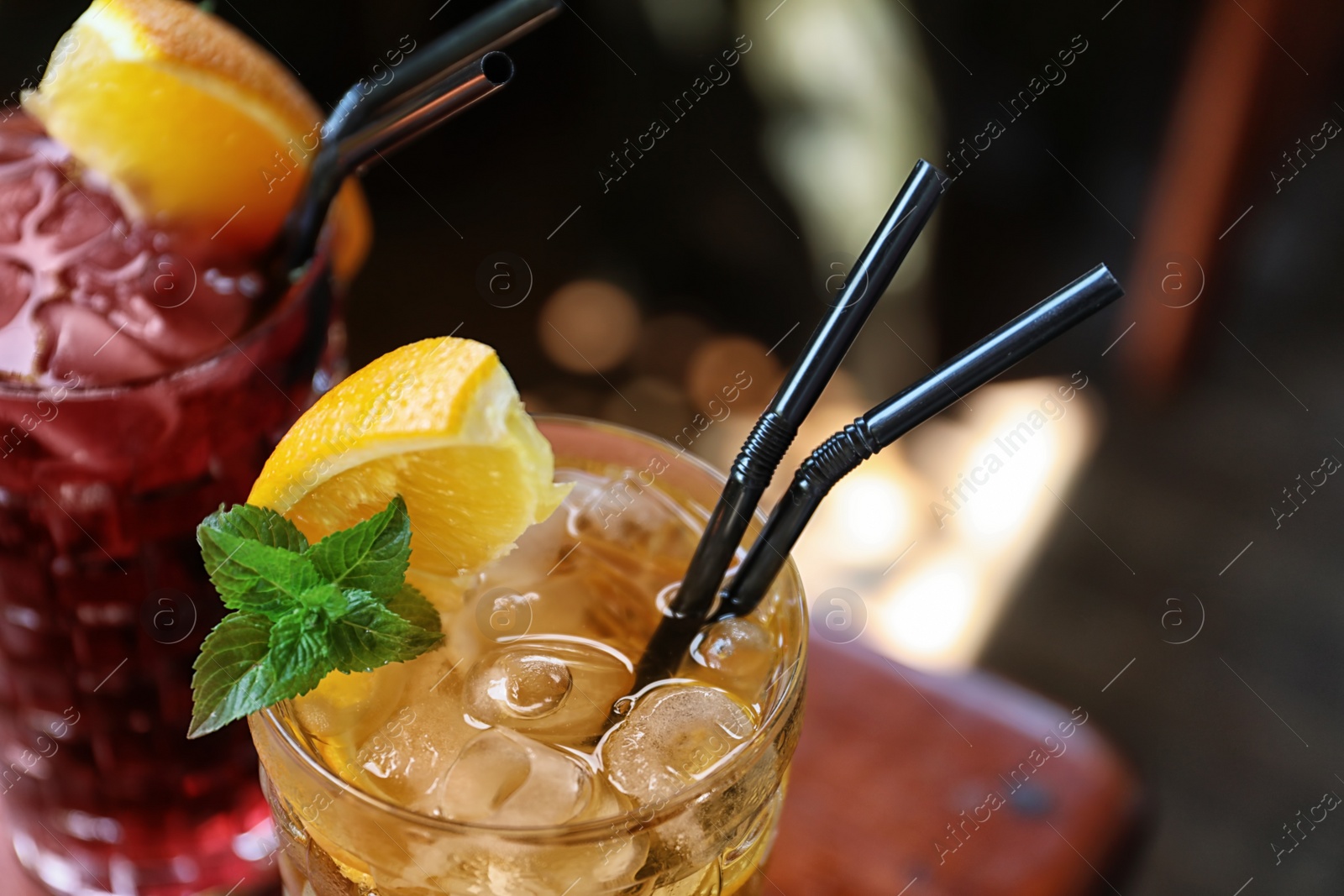 Photo of Glasses of delicious cocktails with ice on blurred background, closeup