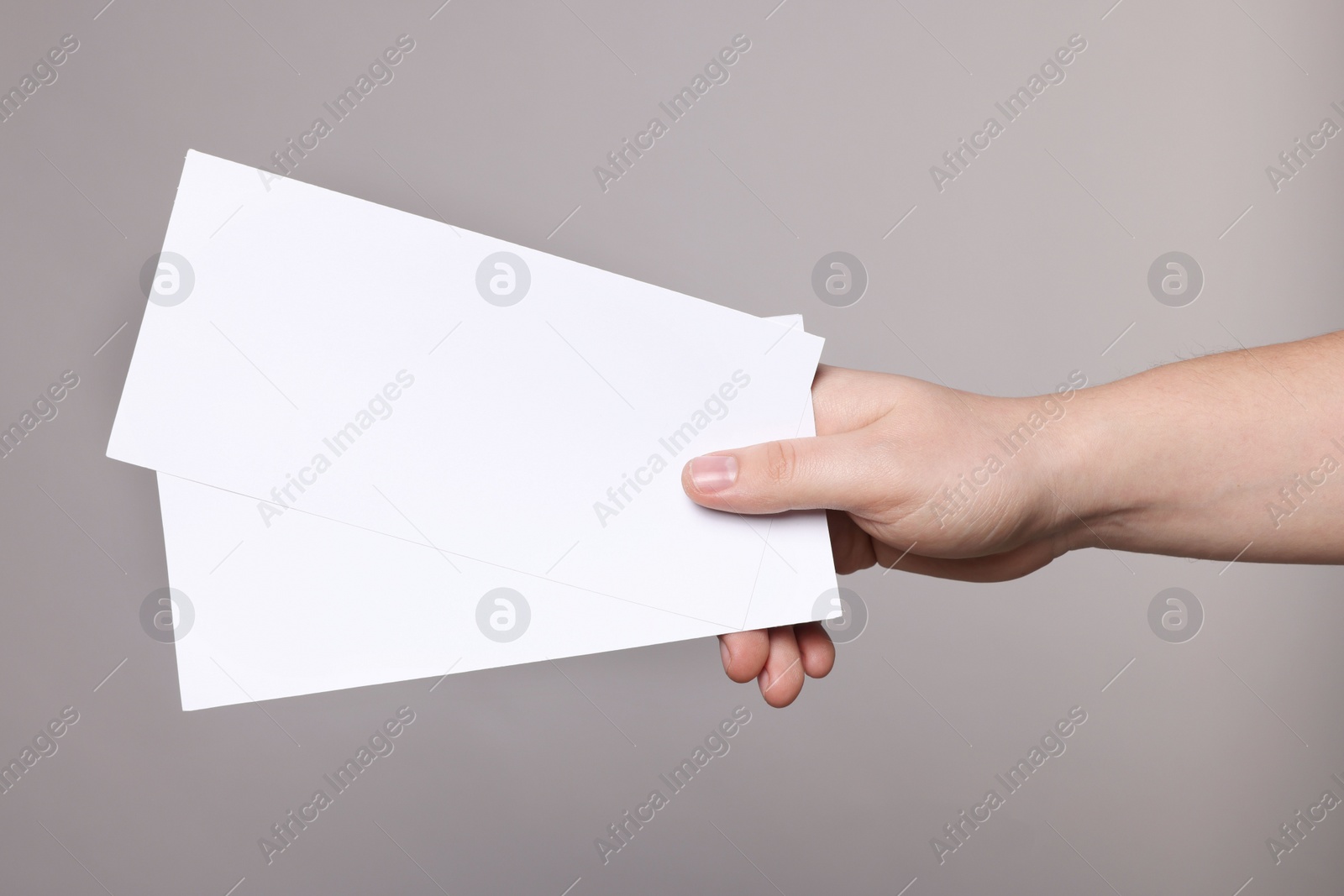 Photo of Woman holding flyers on grey background, closeup. Mockup for design