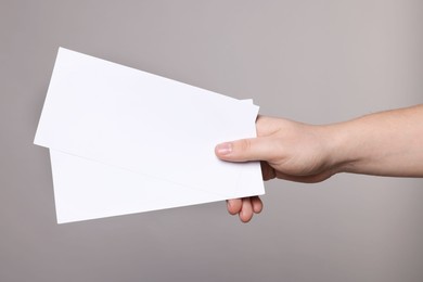 Woman holding flyers on grey background, closeup. Mockup for design