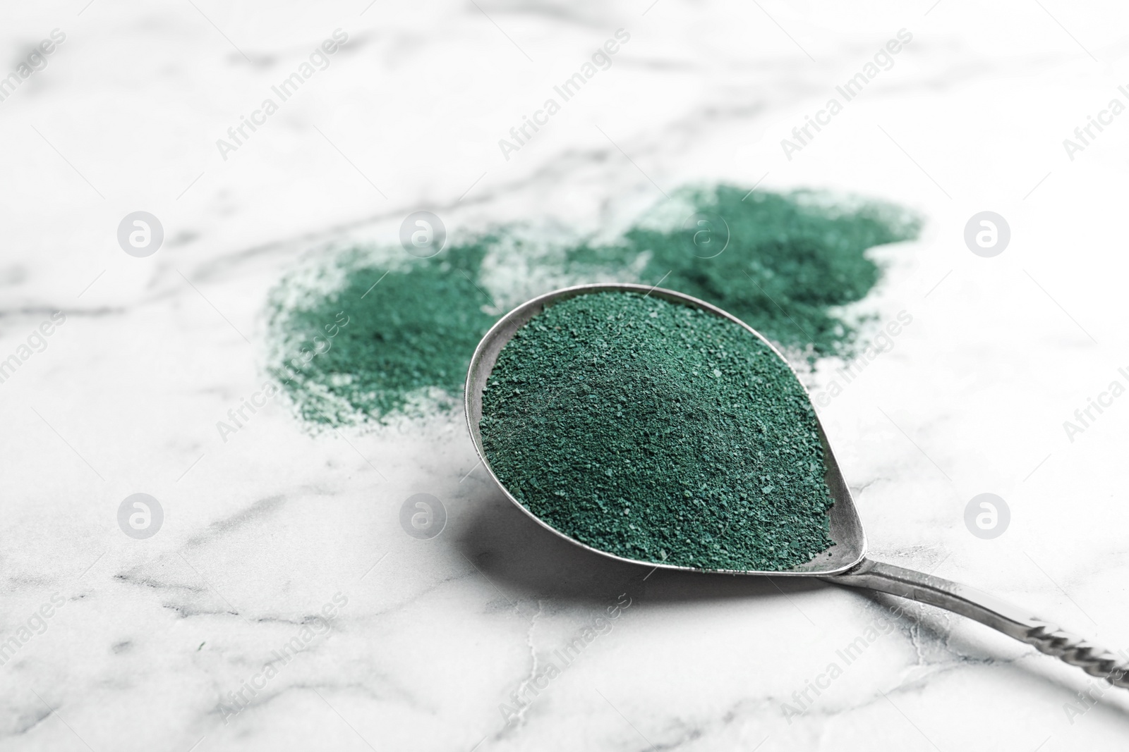 Photo of Spoon of spirulina algae powder on marble background