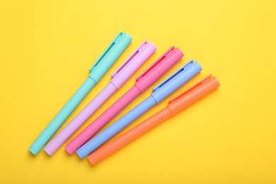 Photo of Many colorful markers on yellow background, above view