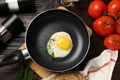 Photo of Delicious fried egg in frying pan on wooden table, flat lay