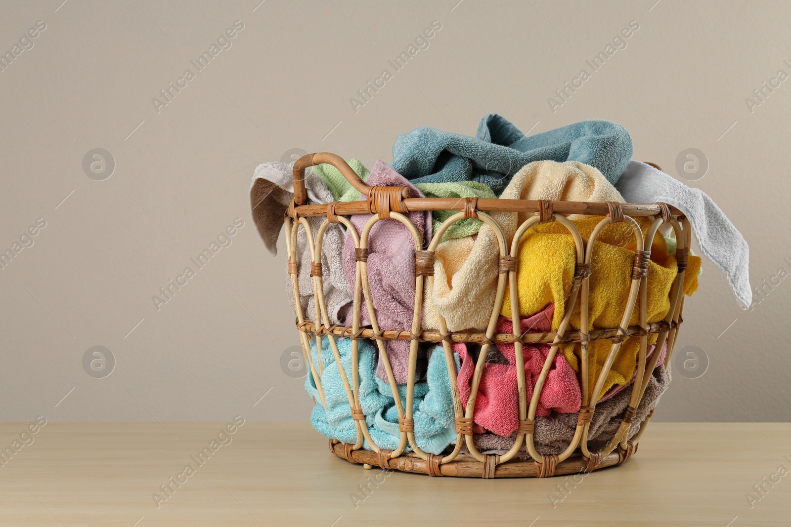 Photo of Wicker laundry basket with towels on wooden table