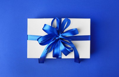 Photo of Beautiful gift box with bow on blue background, top view