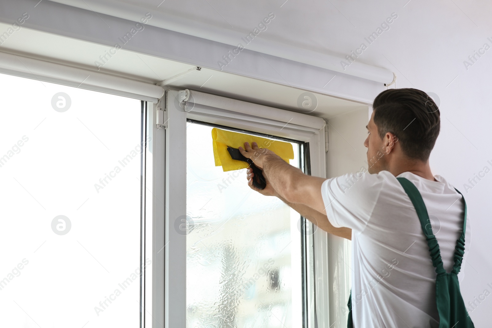 Photo of Professional worker tinting window with foil indoors. Space for text