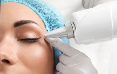 Photo of Woman undergoing laser tattoo removal procedure in salon, closeup