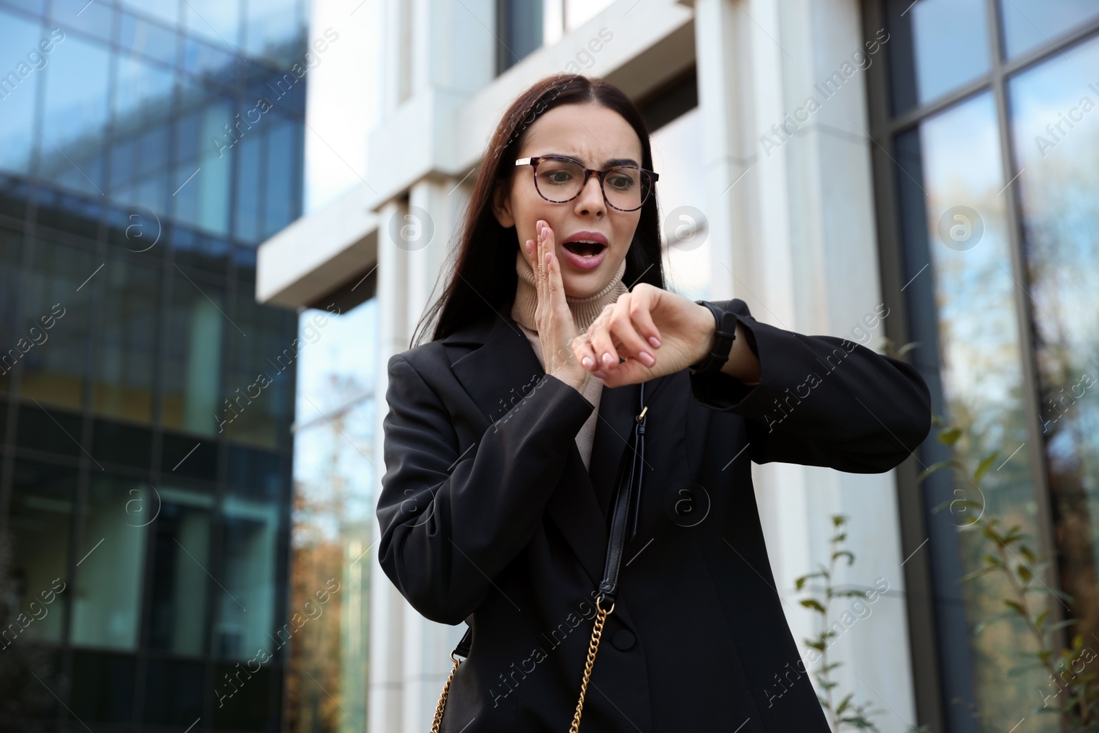 Photo of Emotional woman checking time on watch outdoors. Being late concept