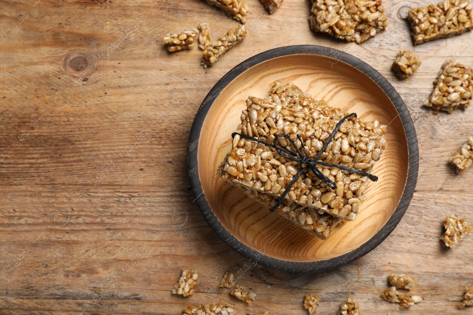 Photo of Delicious sweet kozinaki bars on wooden table, flat lay