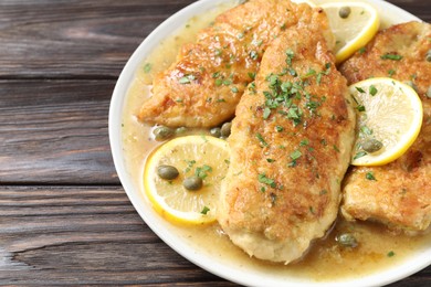 Delicious chicken piccata on wooden table, closeup