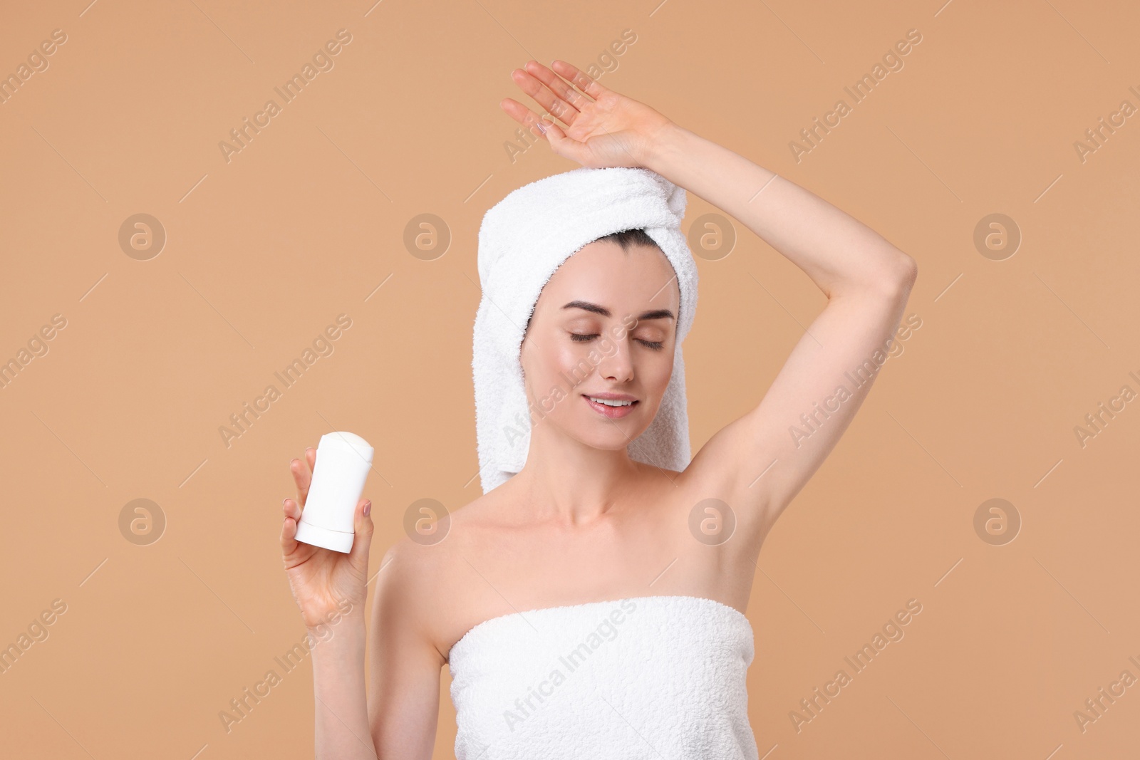 Photo of Beautiful woman applying deodorant on beige background