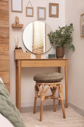 Photo of Stylish dressing table and mirror near white wall indoors. Interior design