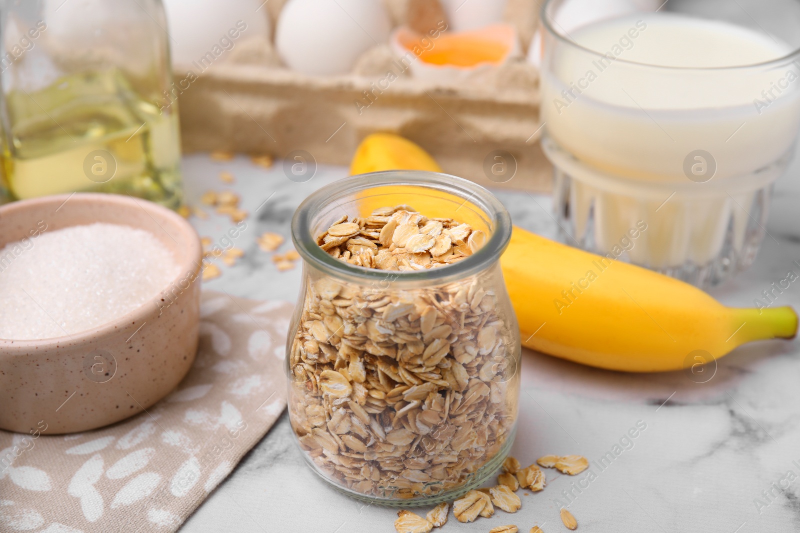 Photo of Different ingredients for cooking tasty oatmeal pancakes on white marble table